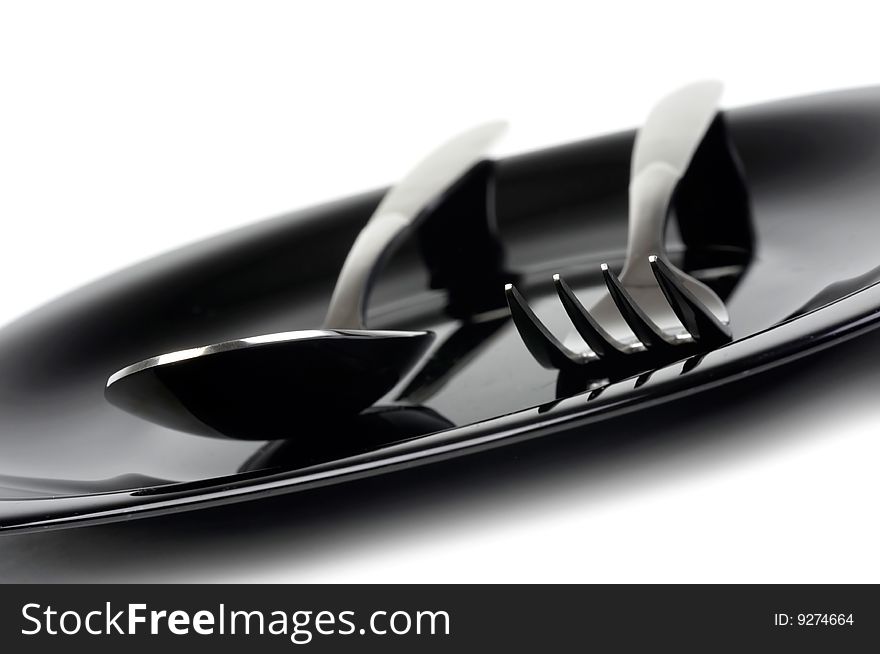 Fork and spoon on black plate. Fork and spoon on black plate