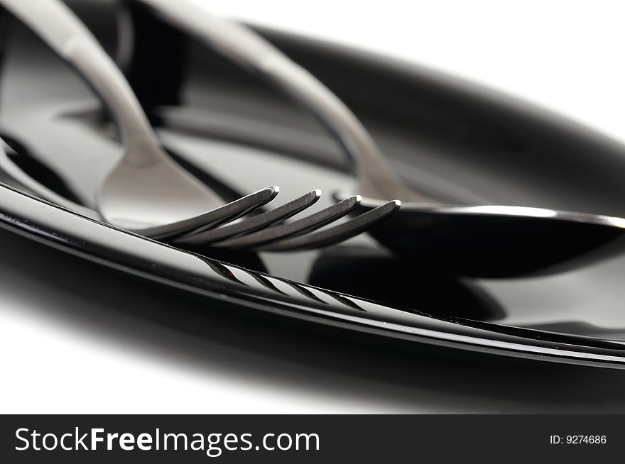Fork and spoon on black plate. Fork and spoon on black plate