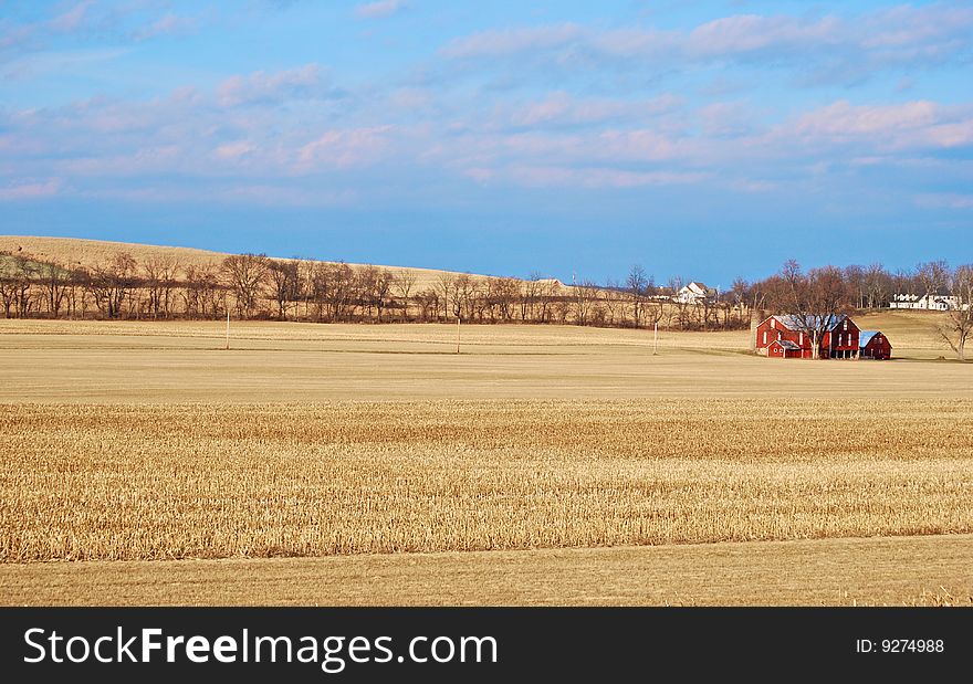 Open field with a red barn in the distance.