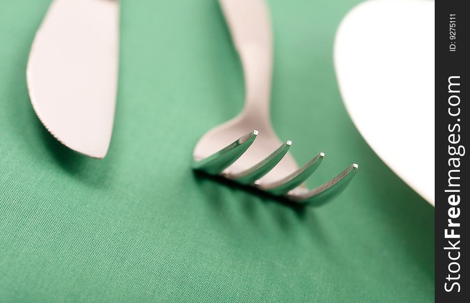 Plate, fork and knife on green background