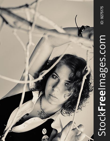 Portrait of a young beautiful girl in black and white with branches in the foreground. Portrait of a young beautiful girl in black and white with branches in the foreground