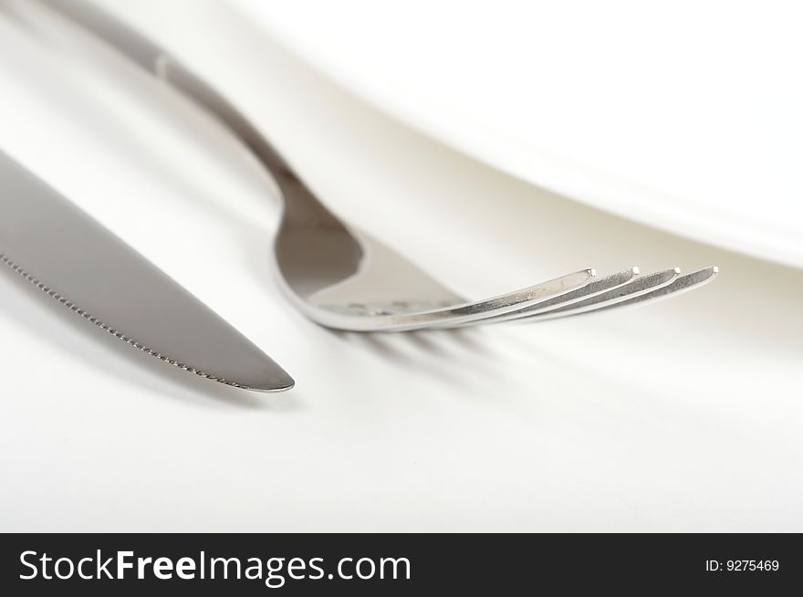 Plate, fork and knife on white background