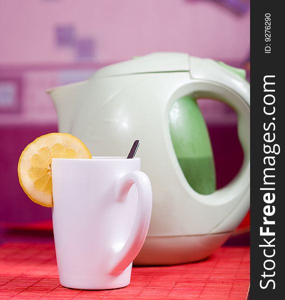 White cup with piece of lemon and kettle. White cup with piece of lemon and kettle