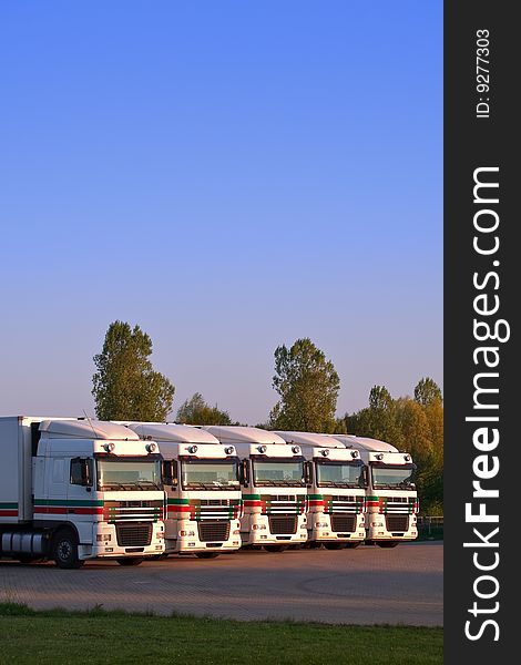 Five trucks in a row with trees and blue sky in the background, copy space