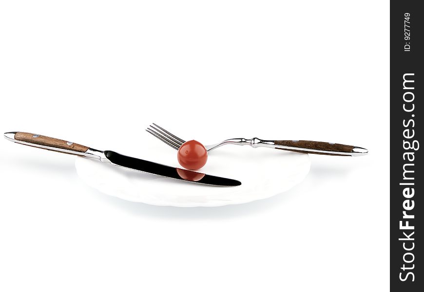 Small tomato on a white plate, knife and fork, isolated image. Small tomato on a white plate, knife and fork, isolated image