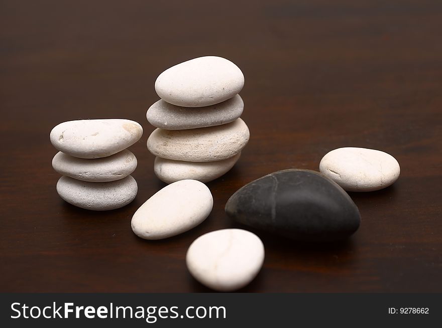 A collection of white and black pebbles arranged on a wood grain. A collection of white and black pebbles arranged on a wood grain.