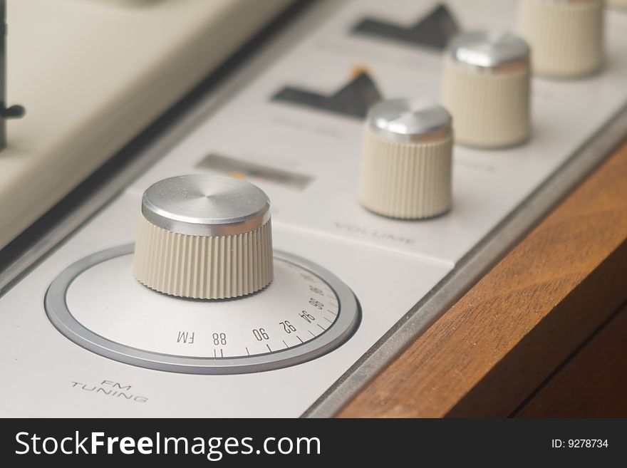 The knobs and dials on an older AM/FM radio and turntable. The knobs and dials on an older AM/FM radio and turntable