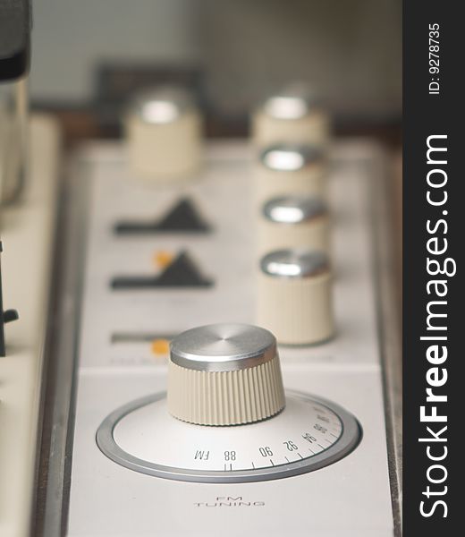 The knobs and dials on an older AM/FM radio and turntable. The knobs and dials on an older AM/FM radio and turntable