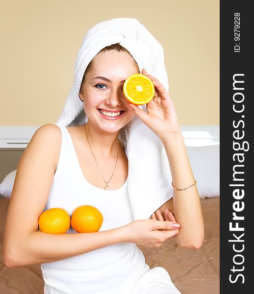 Pretty young woman sitting on the bed at home and eating oranges. Pretty young woman sitting on the bed at home and eating oranges