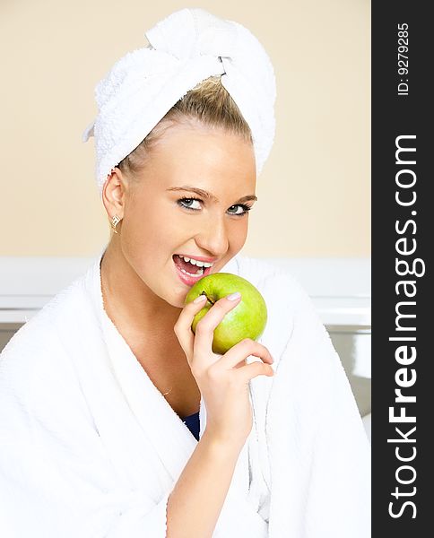 Pretty young woman sitting on the bed at home and eating an apple. Pretty young woman sitting on the bed at home and eating an apple