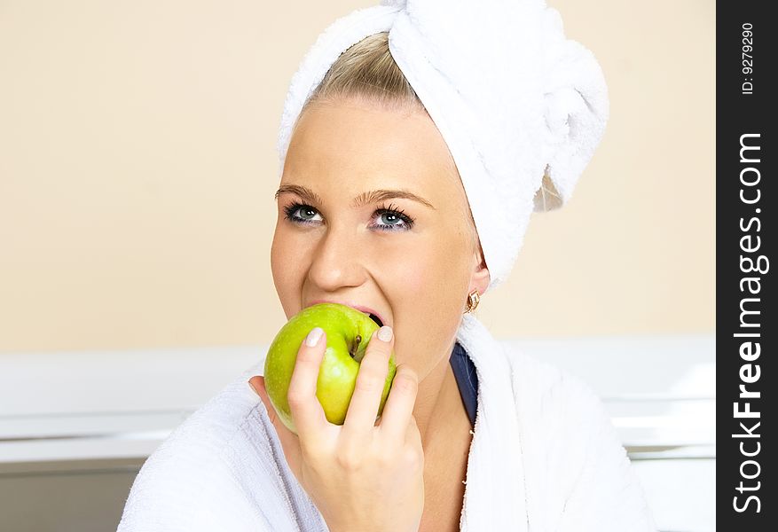 Pretty young woman sitting on the bed at home and eating an apple. Pretty young woman sitting on the bed at home and eating an apple