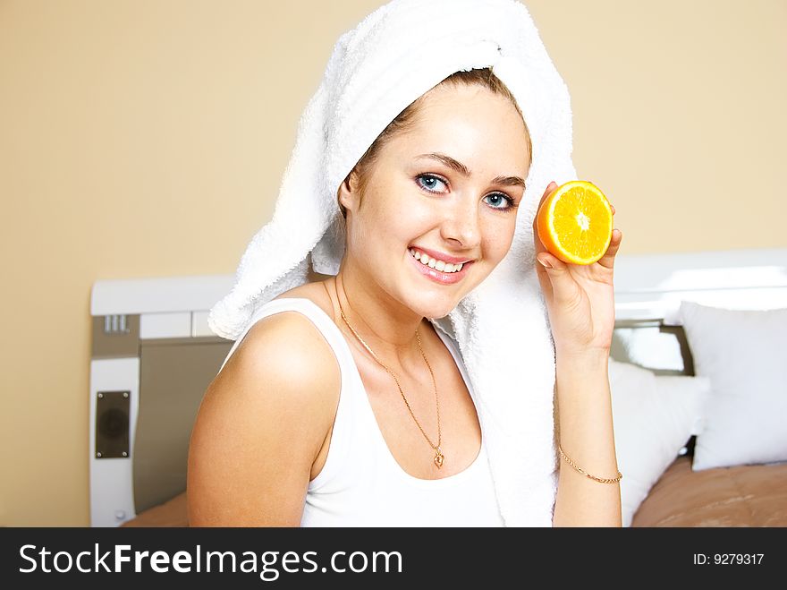 Pretty young woman sitting on the bed at home and eating oranges. Pretty young woman sitting on the bed at home and eating oranges