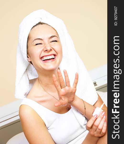 Pretty laughing young woman at home applying nail polish. Pretty laughing young woman at home applying nail polish