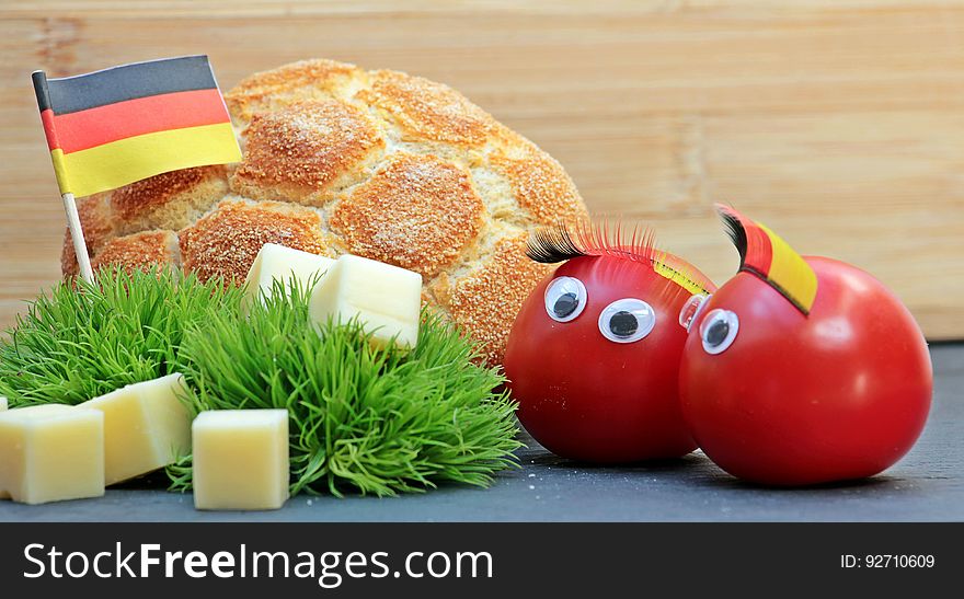 A pair of tomatoes wearing the German flag colors with a football shaped bread. A pair of tomatoes wearing the German flag colors with a football shaped bread.