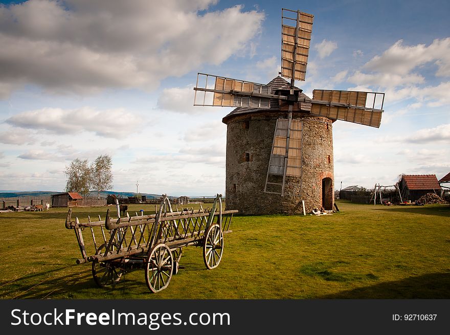 Wooden Windmill Near Wooden Carriage during Daytime