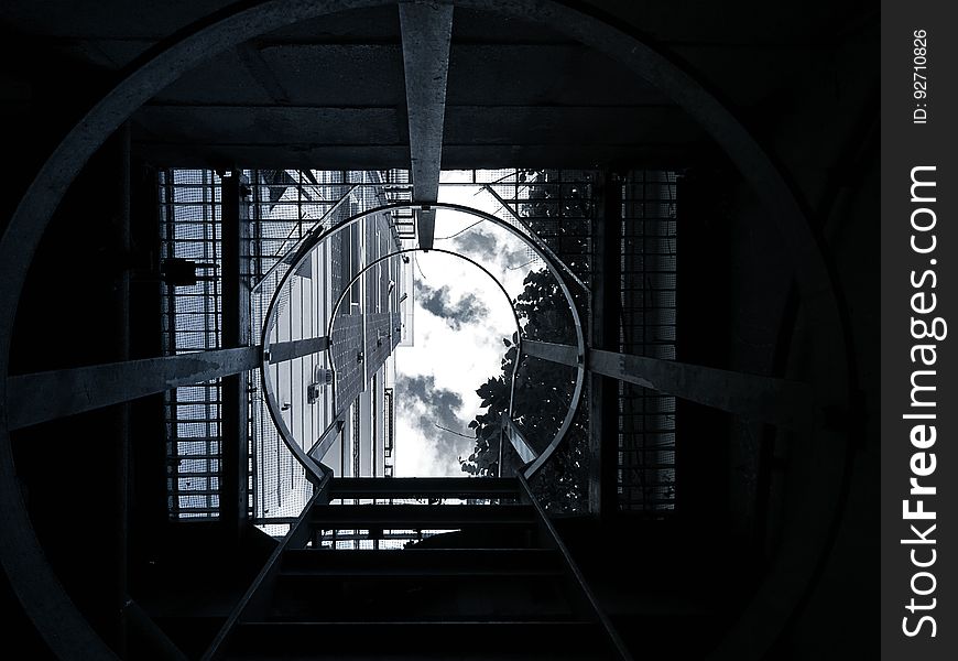 A view from inside a manhole with a ladder rising up to the sky. A view from inside a manhole with a ladder rising up to the sky.