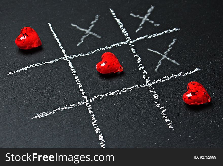 A close up of a chalkboard with a game of tic-tac-toe with hearts instead of naughts. A close up of a chalkboard with a game of tic-tac-toe with hearts instead of naughts.