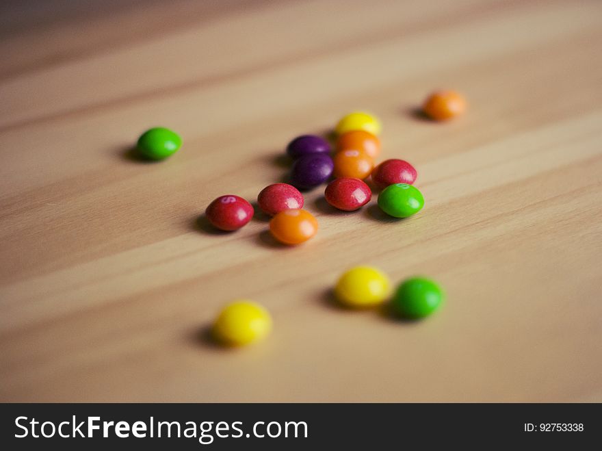 A bunch of colorful Skittles candies on wood background.