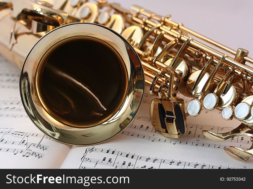 A saxophone on top of sheet music. A saxophone on top of sheet music.