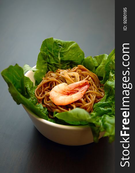 Braised egg noodles with seafood, garnished with shrimp on a bed of romaine lettuce. Braised egg noodles with seafood, garnished with shrimp on a bed of romaine lettuce.