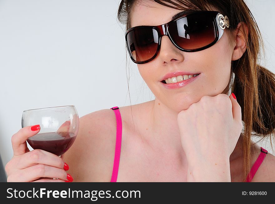 Female fashion model holding a glass of wine wearing summer sun glasses. Female fashion model holding a glass of wine wearing summer sun glasses.