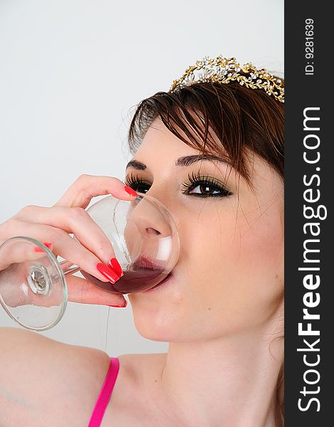 Female fashion model drinking the last of her wine out of a glass with a golden tiara on her head. Female fashion model drinking the last of her wine out of a glass with a golden tiara on her head.