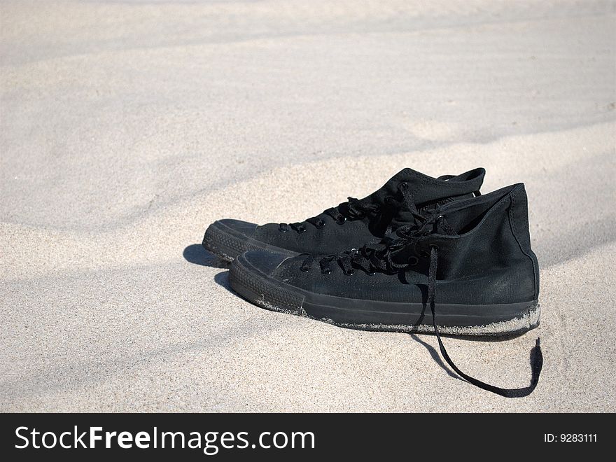 Black male sneakers on a beach. Black male sneakers on a beach