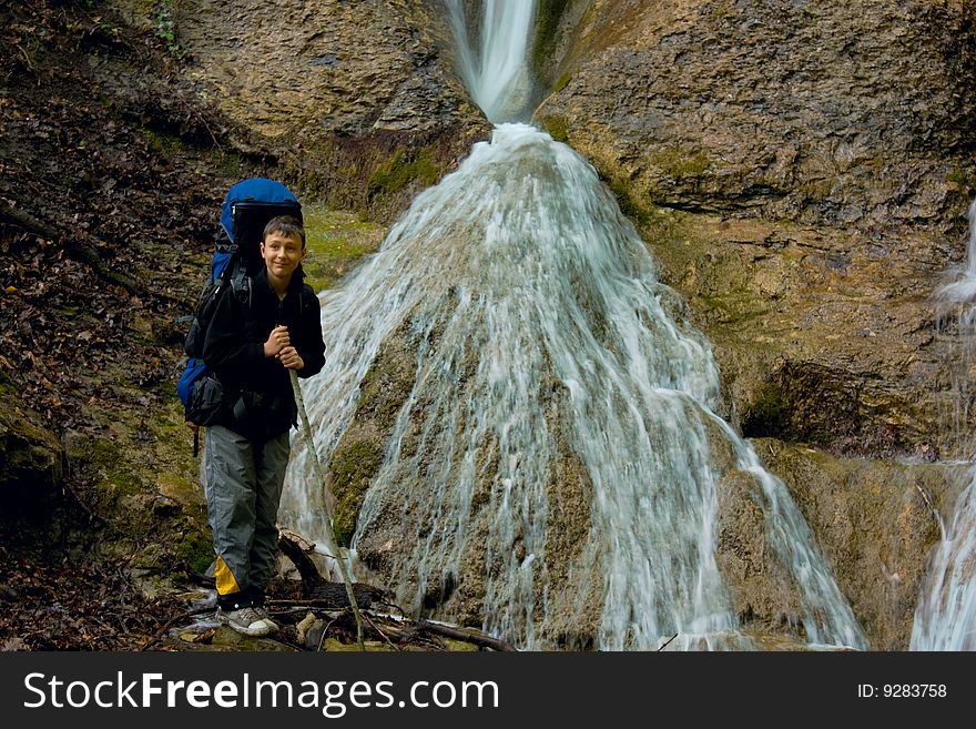 A spring waterfall and boy is hiker in Crimea