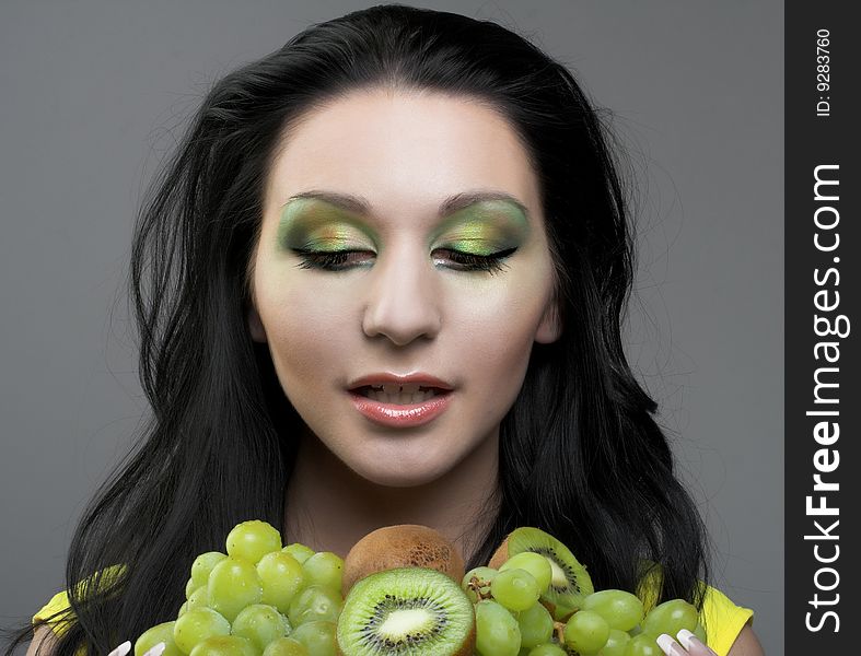 Portrait of young woman witn kiwi and green grapes. Portrait of young woman witn kiwi and green grapes