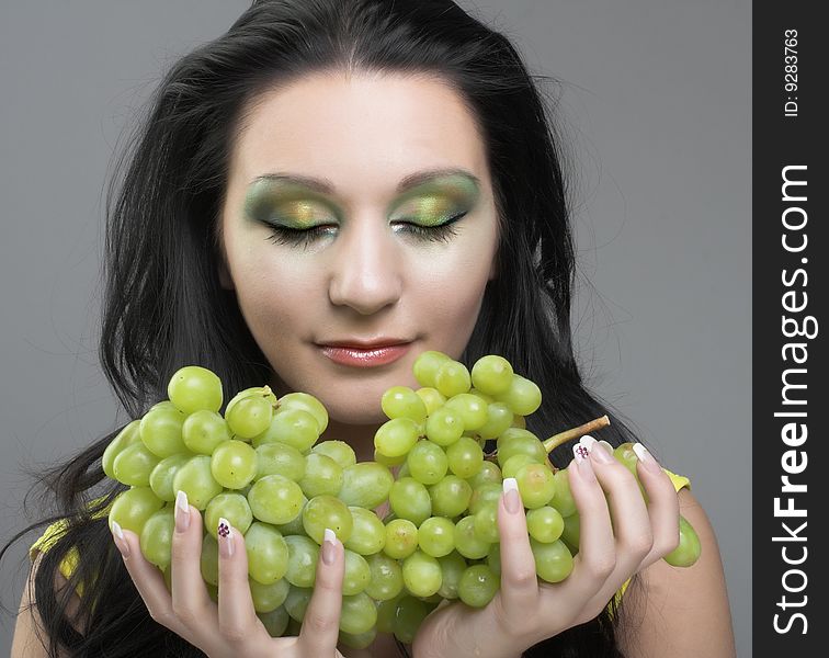 Portrait of young brunette with green grapes. Portrait of young brunette with green grapes