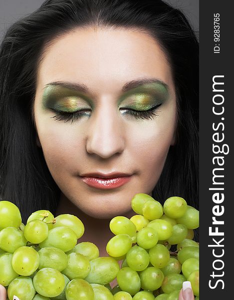 Portrait of young brunette with green grapes. Portrait of young brunette with green grapes