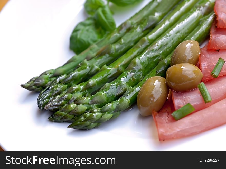 Green asparagus with sausages and olives.