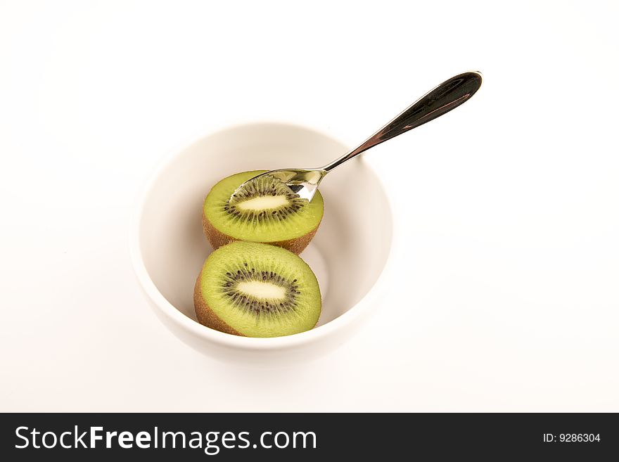 Halved kiwi in a white bowl with spoon. Halved kiwi in a white bowl with spoon