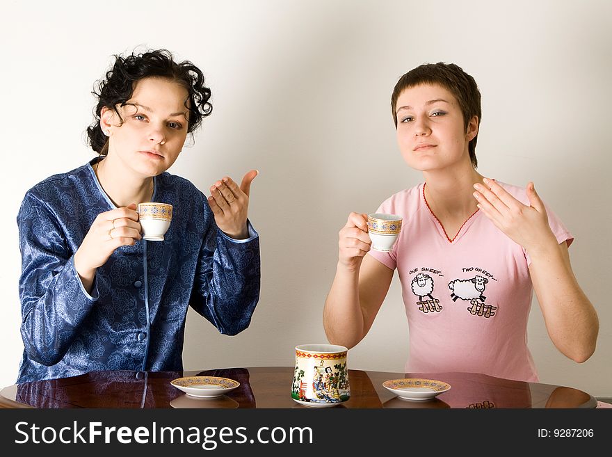 Two young women sitting at a table and drinking a tea. Two young women sitting at a table and drinking a tea