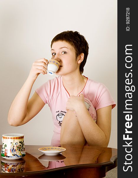 Young woman sitting at a table and drinking a tea. Young woman sitting at a table and drinking a tea