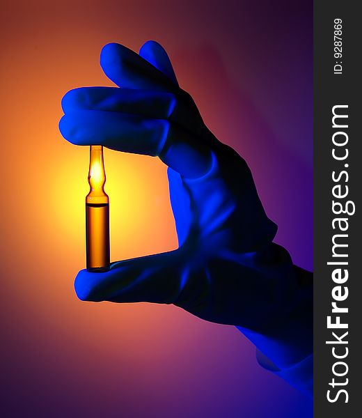 Gloved hand holding an clear ampule with liquid. Abstract circular background. Gloved hand holding an clear ampule with liquid. Abstract circular background.