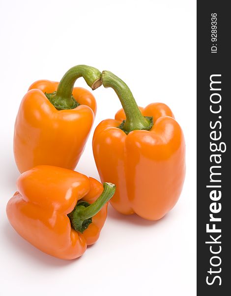 Three orange sweet peppers. Isolated over white background.