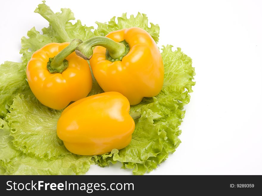 Three sweet peppers on leaf lettuce. Isolated over white background.