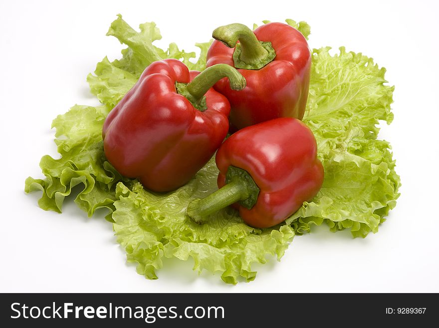 Two red sweet peppers on leaf lettuce. Isolated over white background.