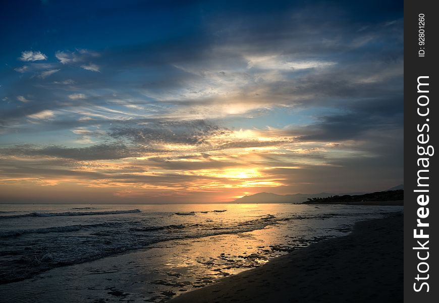 A sunset on a beach with calm seas. A sunset on a beach with calm seas.