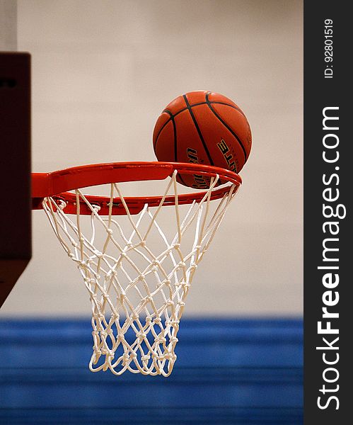 A basketball hovers on the rim of a net. A basketball hovers on the rim of a net.