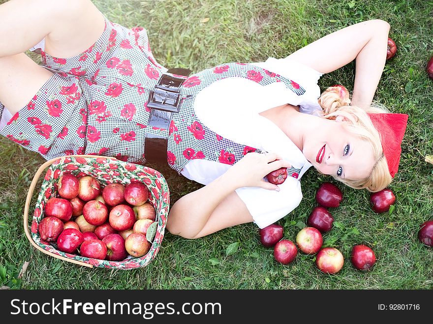 Woman In Gray And White Rose Print Onesies Laying On Grass Beside Red Apple Fruits