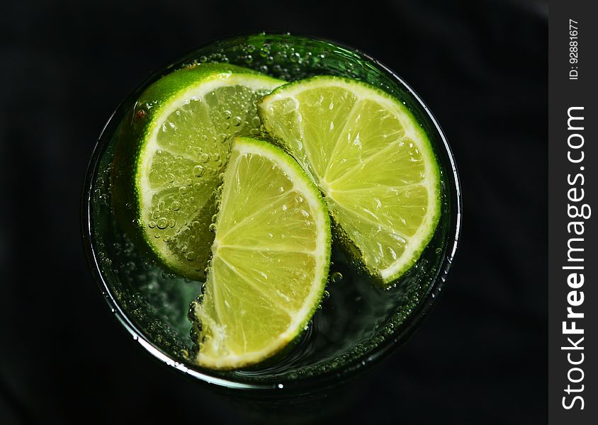 A glass with slices of green lime. A glass with slices of green lime.