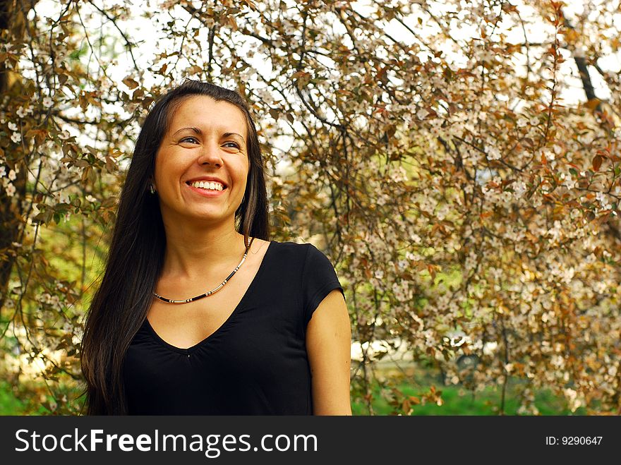 Young woman smiles in the spring blossoming garden