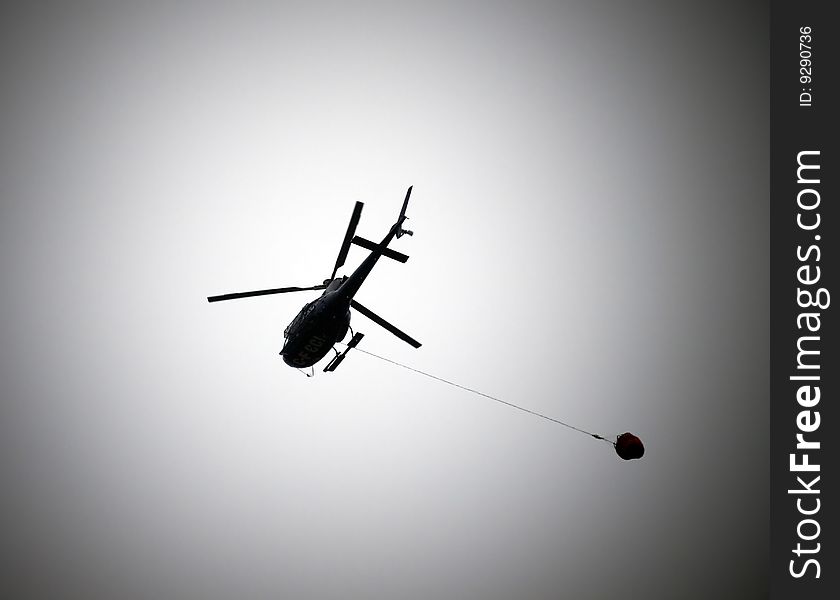 Helicopter on a dark gray sky transporting food. Helicopter on a dark gray sky transporting food