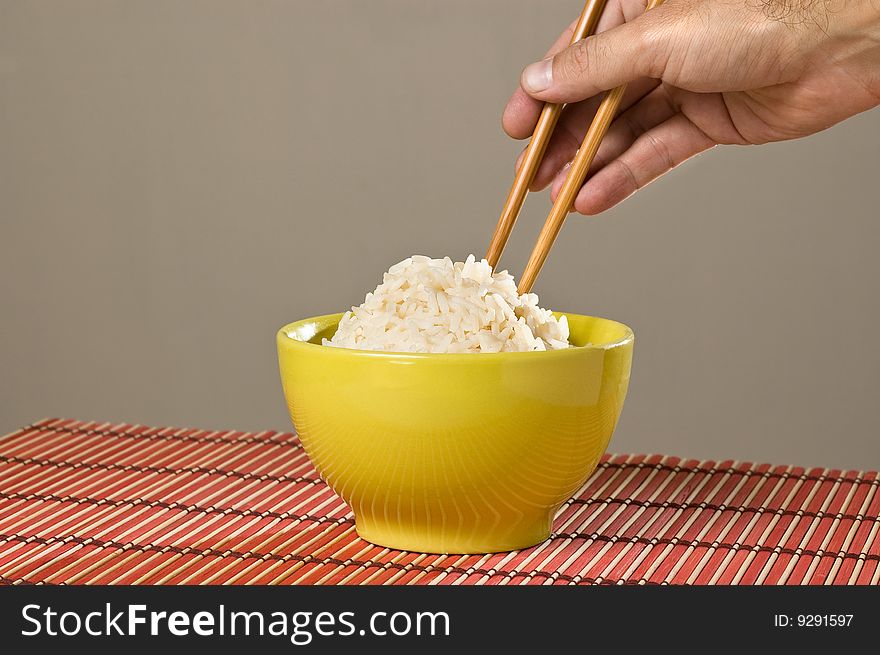 Hand with Chinese chopsticks with a bowl of rice. Hand with Chinese chopsticks with a bowl of rice