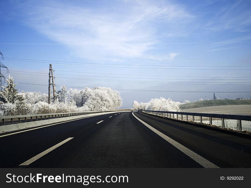 A highway in wintertime with white trees and a white landscape. A highway in wintertime with white trees and a white landscape.