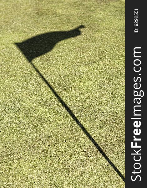 Amazing green golf field showing the hole and the flag shadow, without ball. Amazing green golf field showing the hole and the flag shadow, without ball