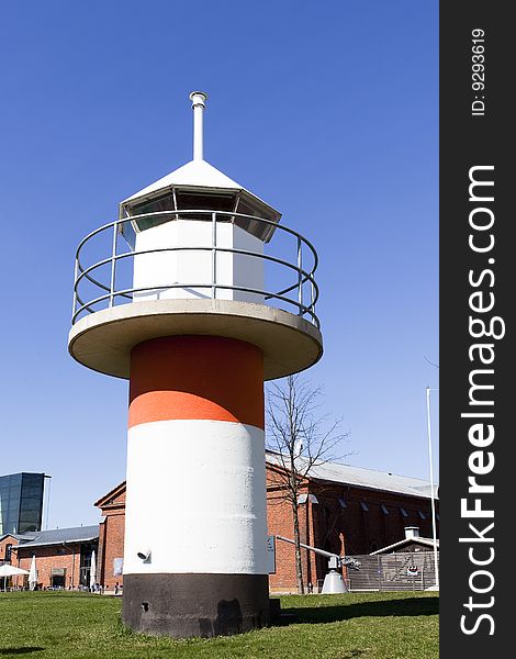 Model of a lighthouse on shore , blue sky backdrop.