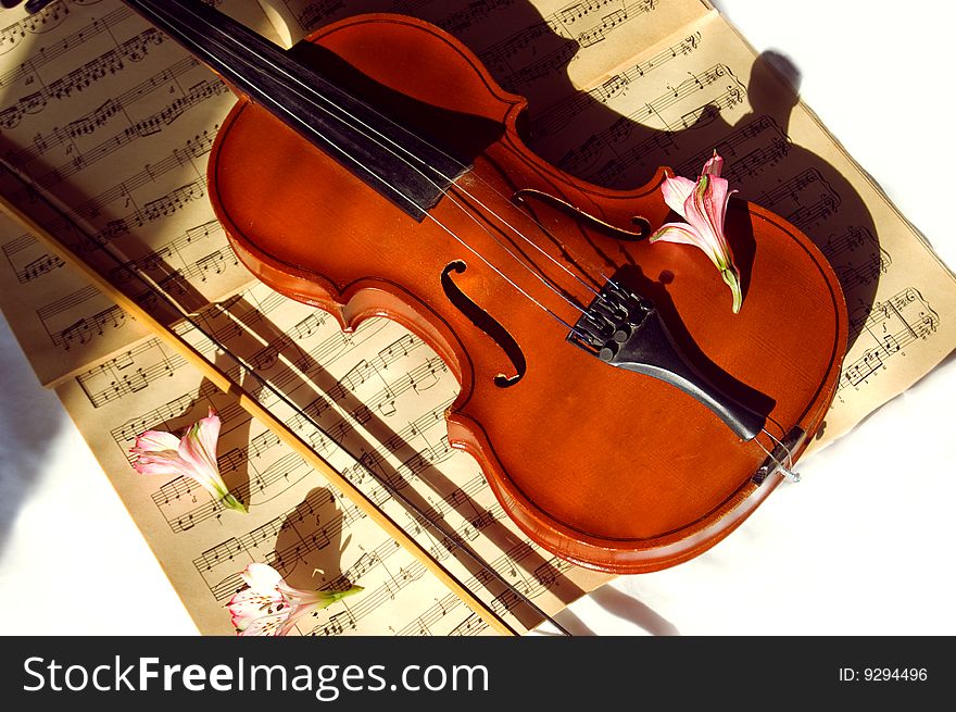 Old violin, fiddle-stick and music sheet over white